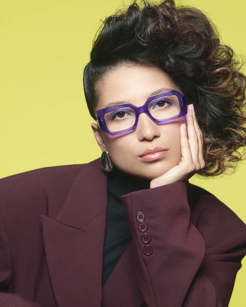 Model mit markanter violetter WOOW-Fassung vor gelbem Hintergrund